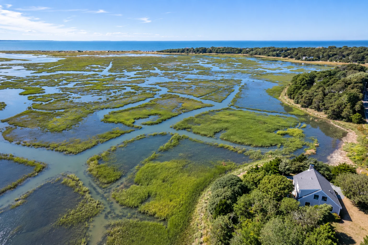 Aerial view of Herring Brook House beside the tidal estuary, with Cape Cod Bay beyond